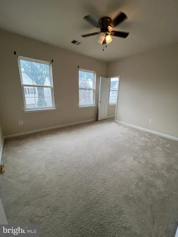 an empty room with windows and ceiling fan