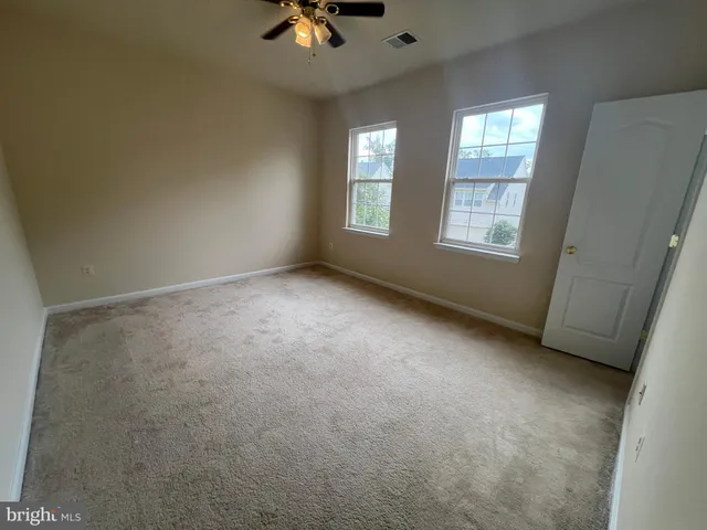 an empty room with windows and chandelier fan