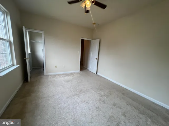 an empty room with chandelier fan and windows