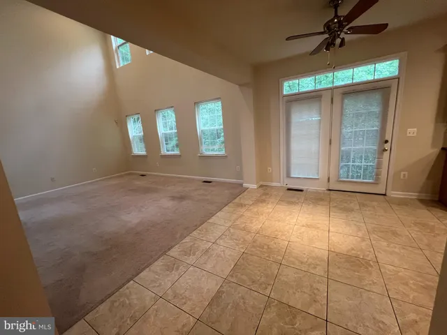 an empty room with windows and ceiling fan