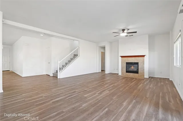 a view of an empty room with wooden floor fireplace and a window