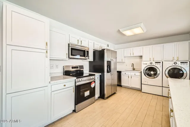 a kitchen with a refrigerator a stove top oven a sink dishwasher and white cabinets with wooden floor