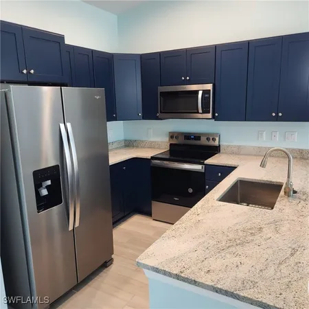 a kitchen with a sink and a stove with wooden floor