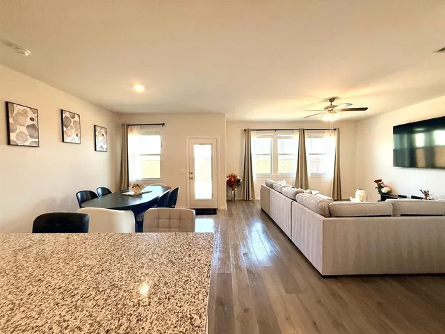 a living room with stainless steel appliances kitchen island granite countertop furniture and a large window