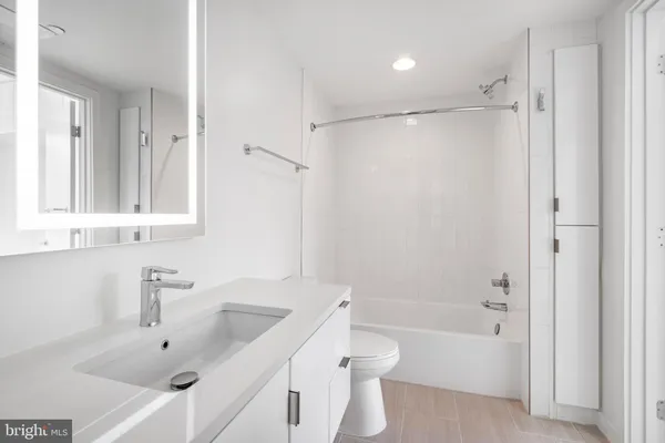 a bathroom with a bathtub shower sink vanity and toilet