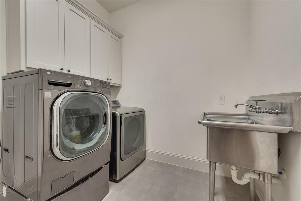 2021 Calisto Way Allen, TX 75013 - Photo 24 of 34 Utility room featuring upper cabinetry with dark hardware, a stainless steel utility sink with a wall-mounted faucet, and light-toned tile flooring
