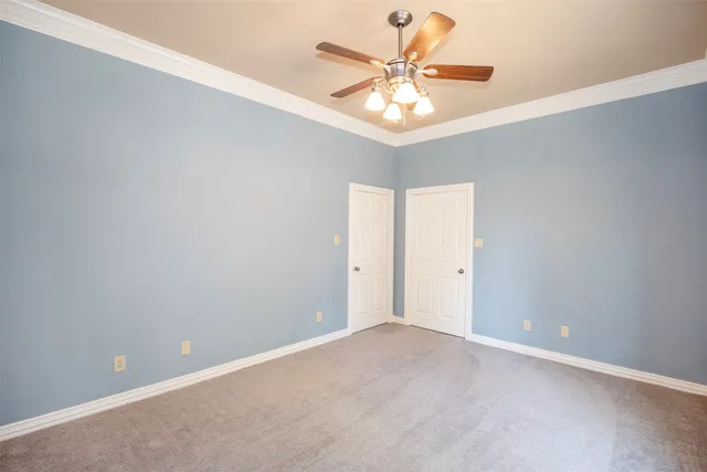 an empty room with a chandelier fan and a wooden floor