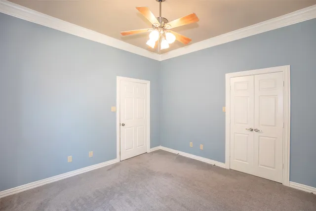 an empty room with a chandelier fan and windows