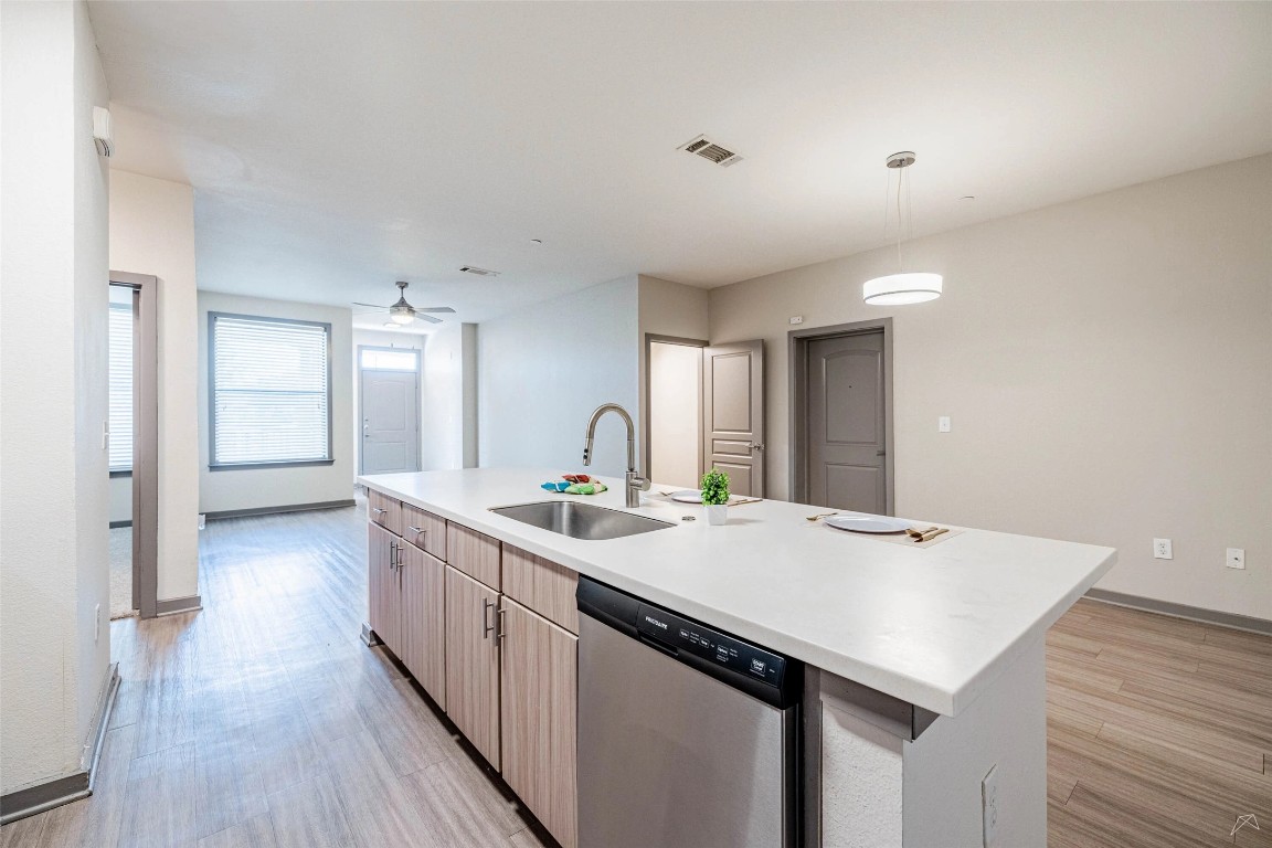 8515 Interstate 35, Unit 11102 Austin, TX 78744 - Photo 5 of 25 Kitchen with dishwasher, a center island with sink, pendant lighting, ceiling fan, and light wood finished floors