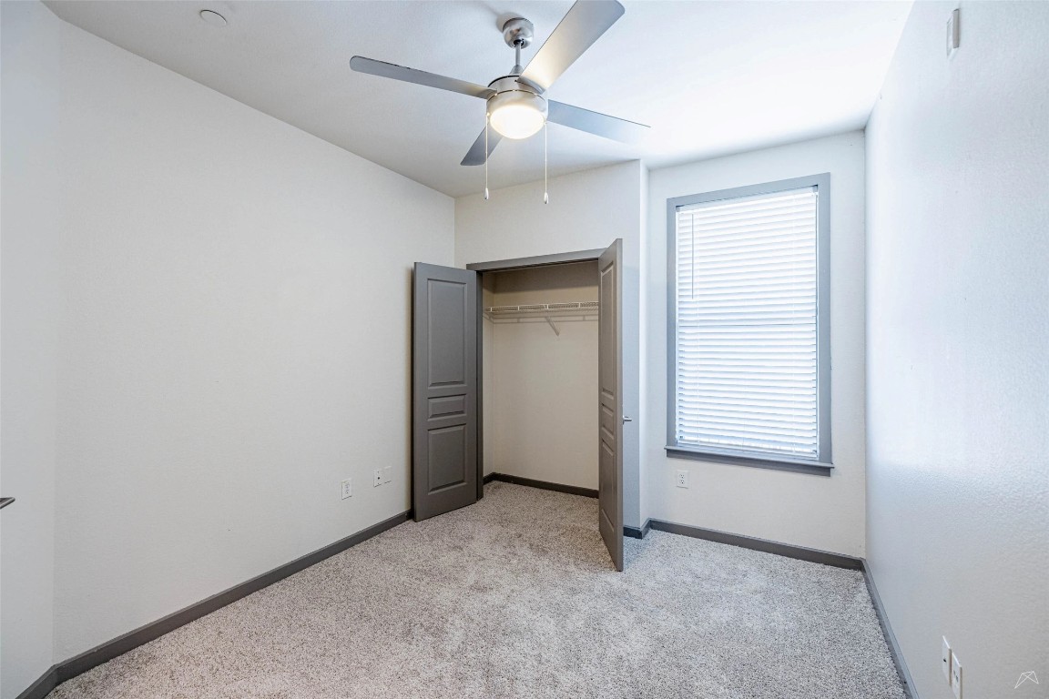 8515 Interstate 35, Unit 11102 Austin, TX 78744 - Photo 8 of 25 Unfurnished bedroom featuring light carpet, a ceiling fan, and a closet
