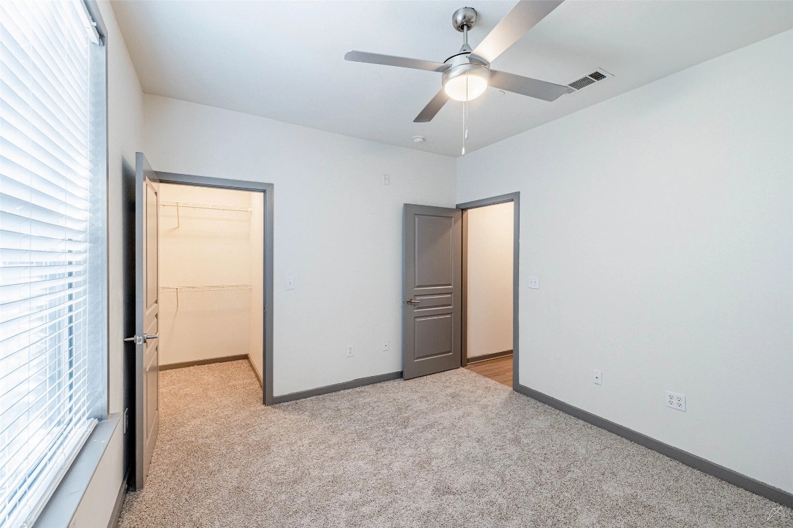 8515 Interstate 35, Unit 11102 Austin, TX 78744 - Photo 9 of 25 Unfurnished bedroom with a spacious closet, light colored carpet, and a ceiling fan
