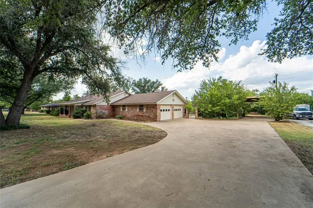 a view of a house with a yard and large trees