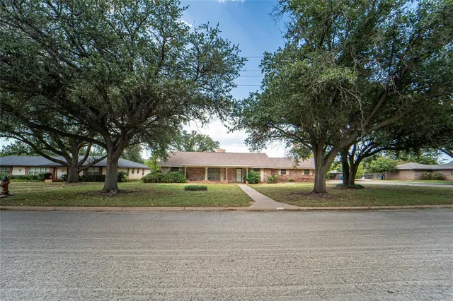 a front view of a house with a yard and trees