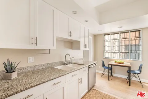 a kitchen with granite countertop a sink white cabinets and white appliances