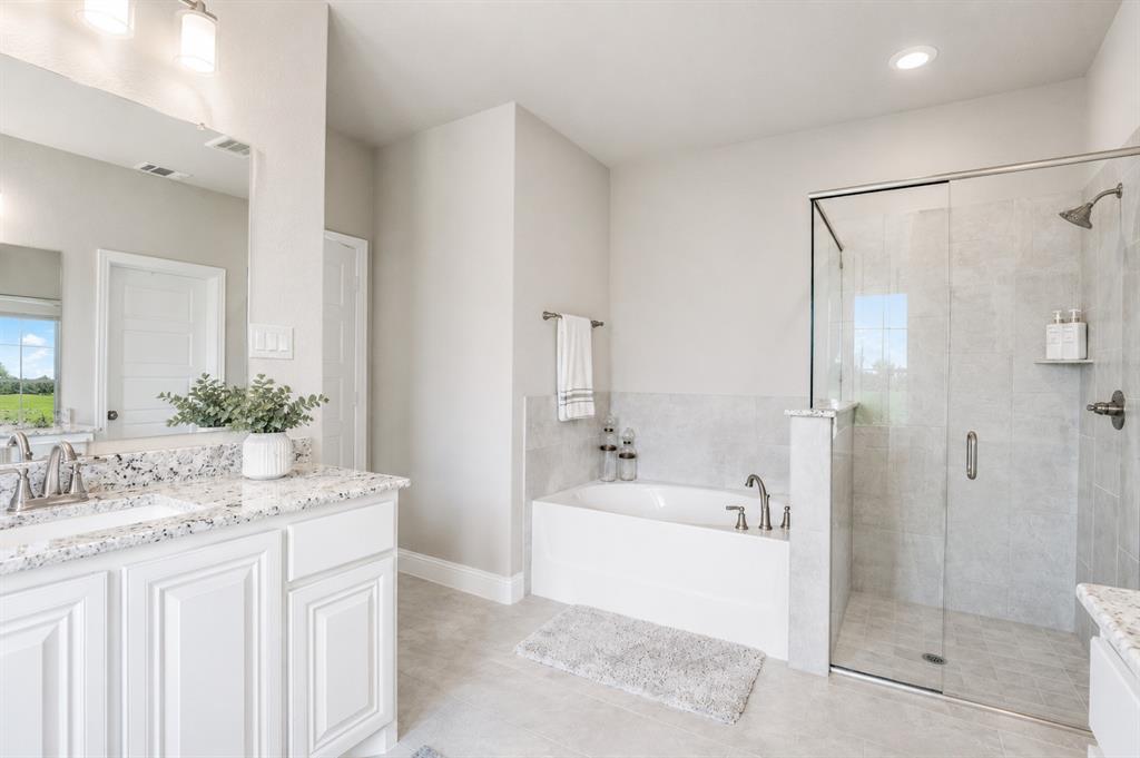 25 Morrison Road Howe, TX 75459 - Photo 11 of 27 Bathroom featuring a dual-sink vanity with a speckled countertop, white cabinetry, a built-in soaking tub, and a glass-enclosed shower with tile surround