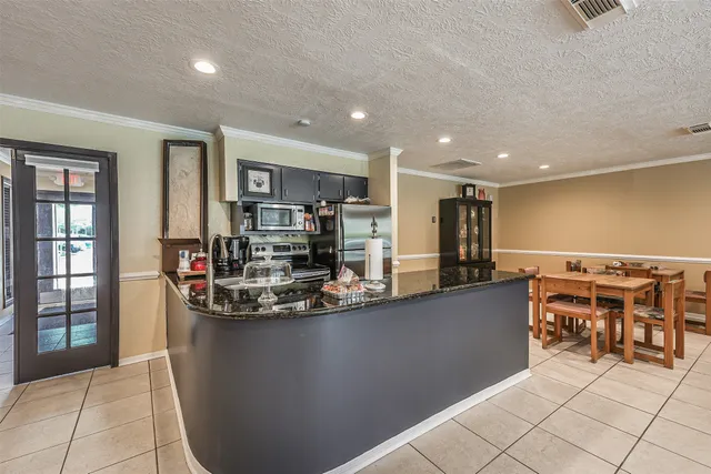 a living room with stainless steel appliances furniture and a kitchen view