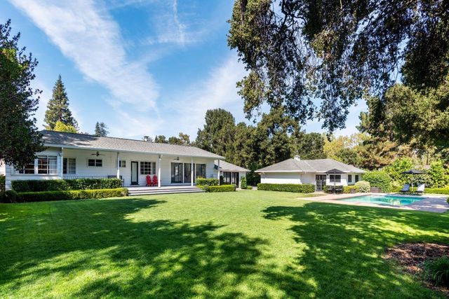 a view of a house with a big yard and sitting area