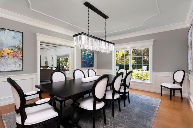 a dining room with furniture a rug a potted plant and wooden floor