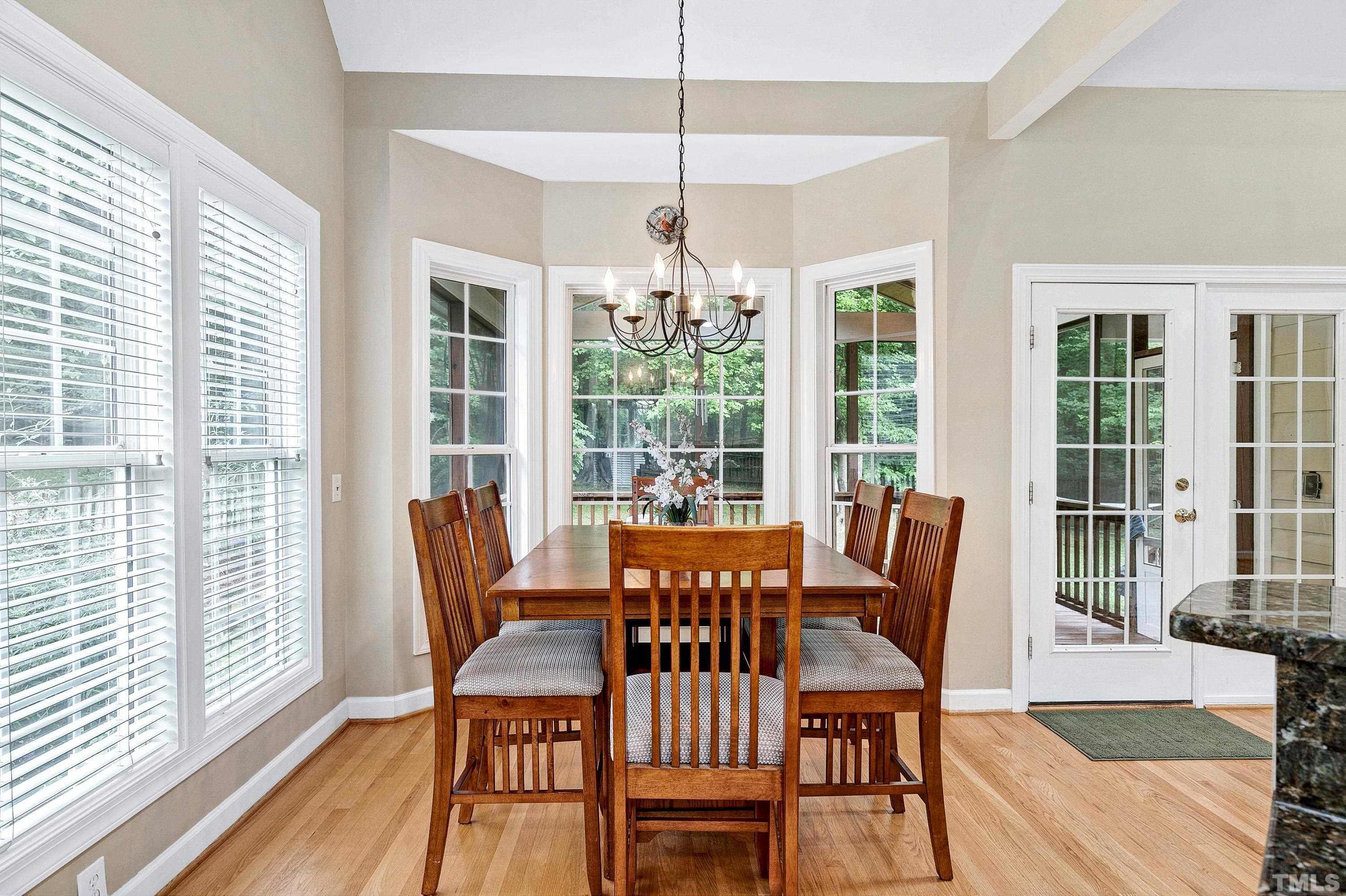 909 Cedar Downs Drive Raleigh, NC 27607 - Photo 11 of 32 a dining room with wooden floor a chandelier a glass table and chairs