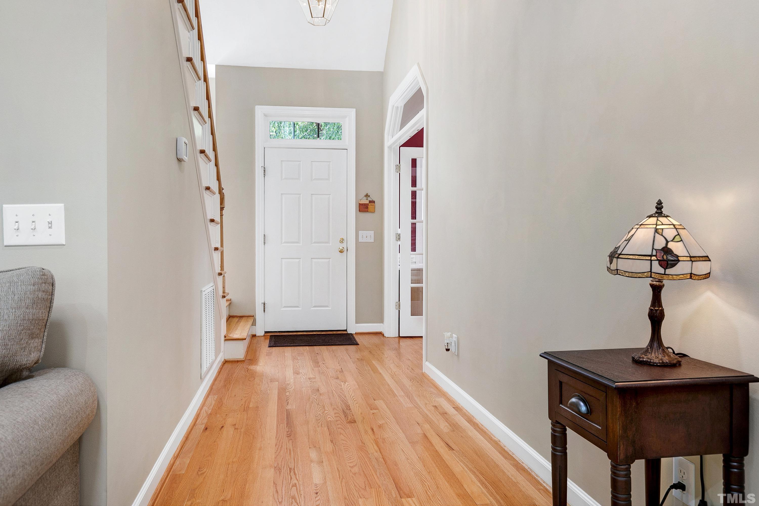 909 Cedar Downs Drive Raleigh, NC 27607 - Photo 5 of 32 a view of a hallway with entryway wooden floor and front door