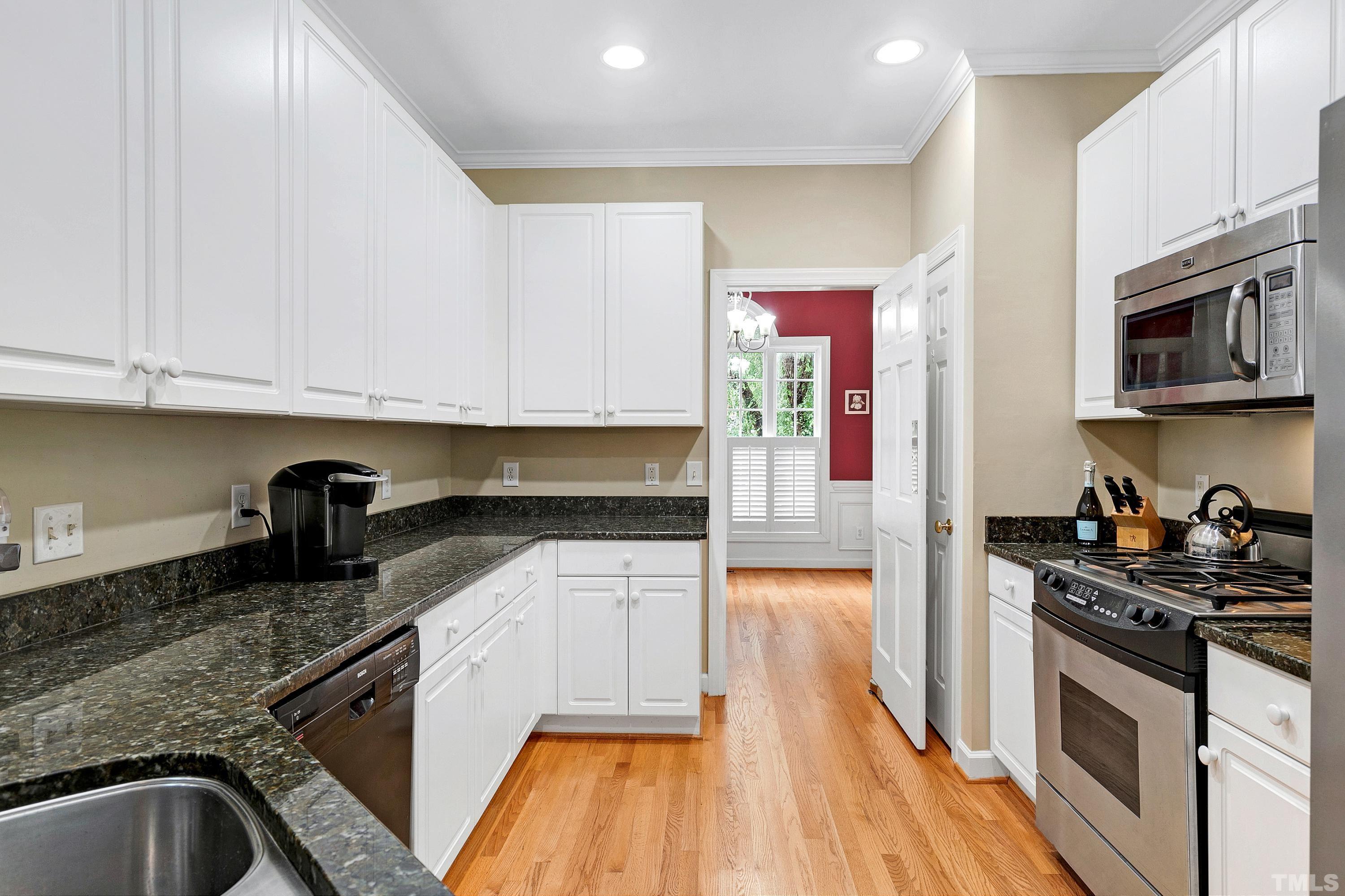 909 Cedar Downs Drive Raleigh, NC 27607 - Photo 9 of 32 a kitchen with granite countertop stainless steel appliances and wooden cabinets