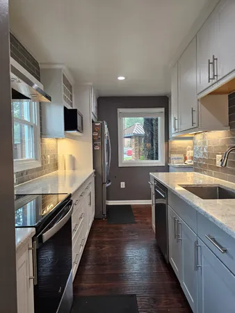 a large kitchen with stainless steel appliances granite countertop a lot of counter space and wooden floors