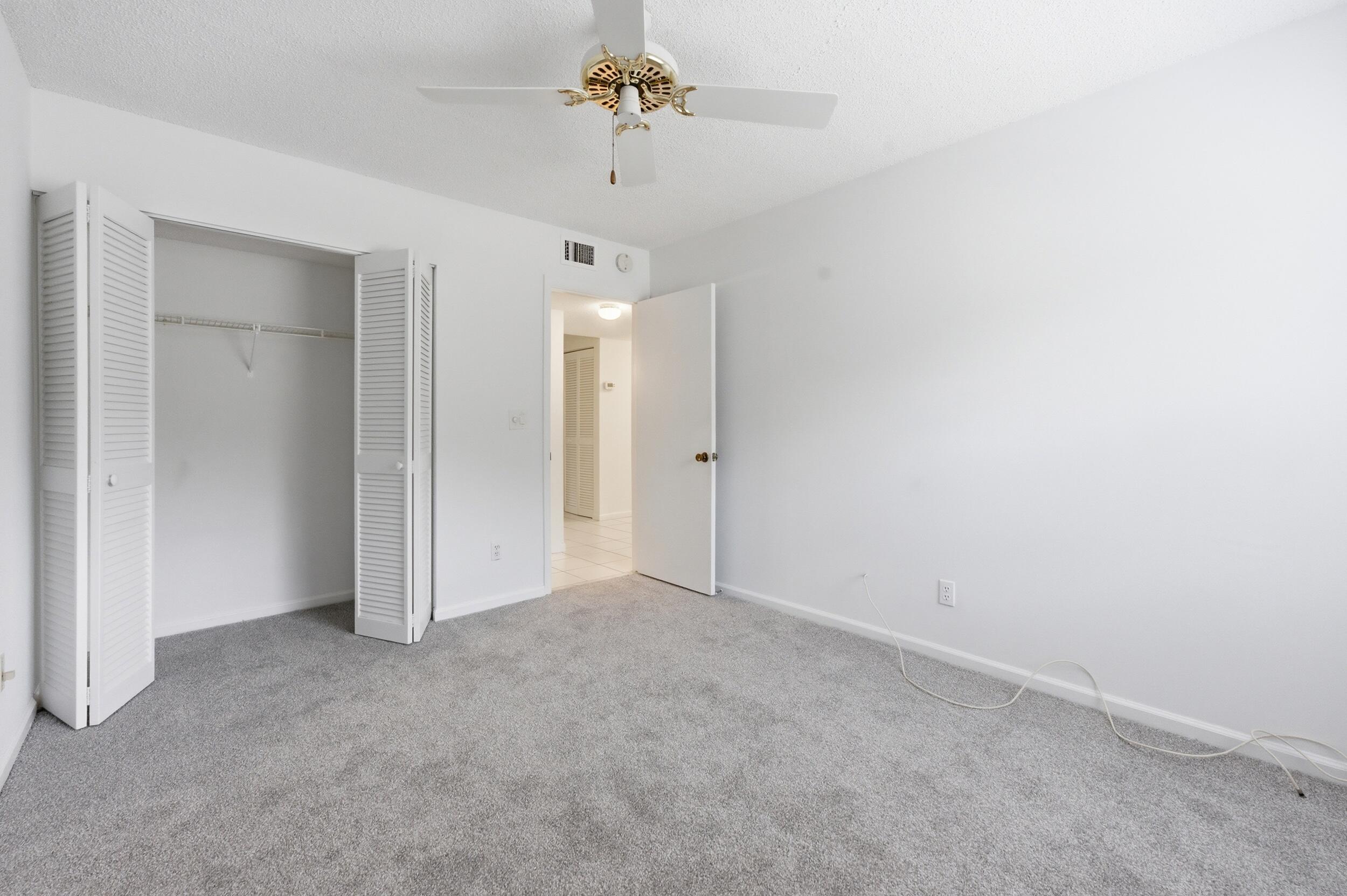 9633 Riverside Drive, Unit E3 Coral Springs, FL 33071 - Photo 17 of 31 an empty room with chandelier fan and closet area