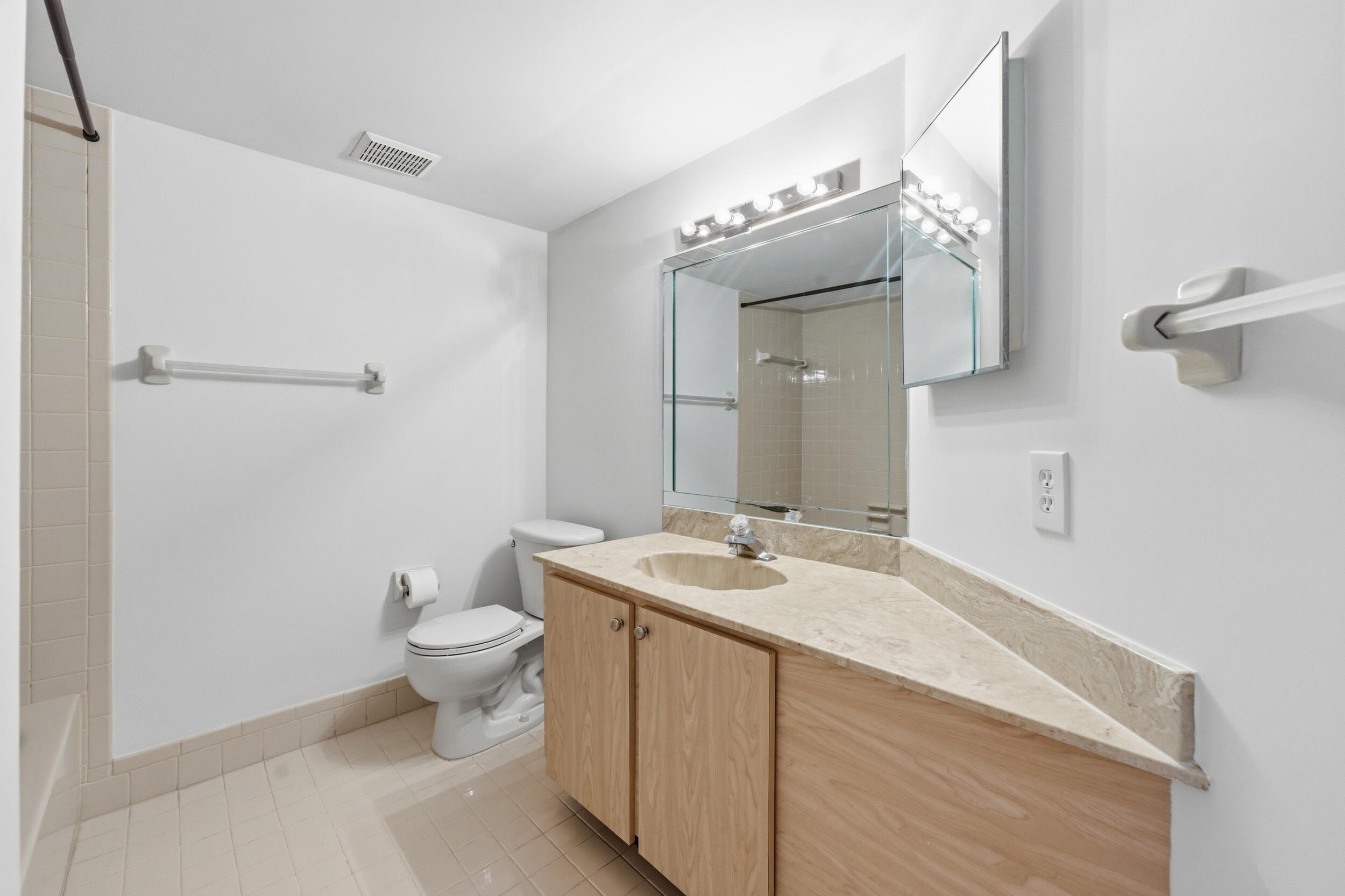 9633 Riverside Drive, Unit E3 Coral Springs, FL 33071 - Photo 20 of 31 a spacious bathroom with a granite countertop sink a toilet and a mirror