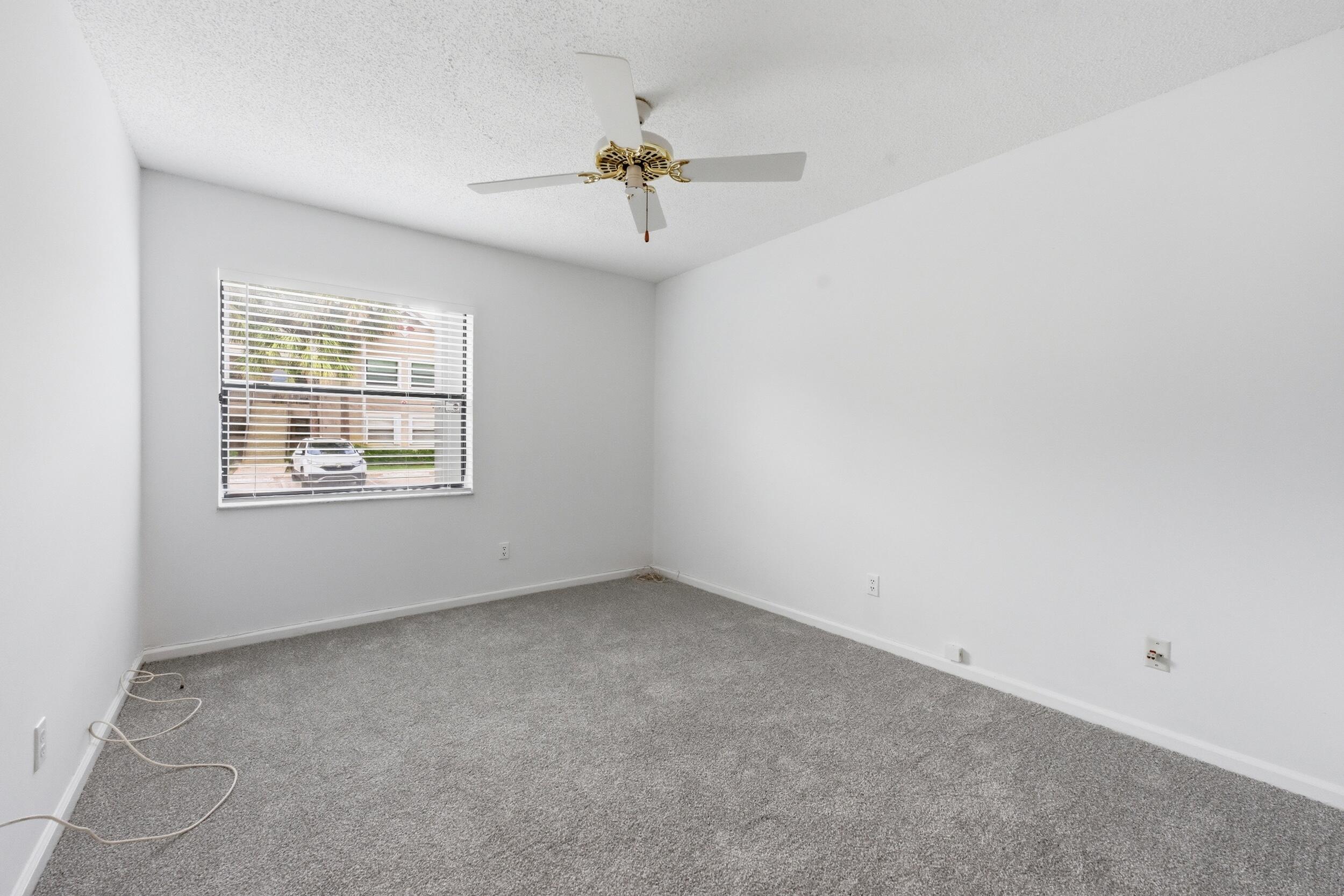 9633 Riverside Drive, Unit E3 Coral Springs, FL 33071 - Photo 22 of 31 an empty room with windows and chandelier fan
