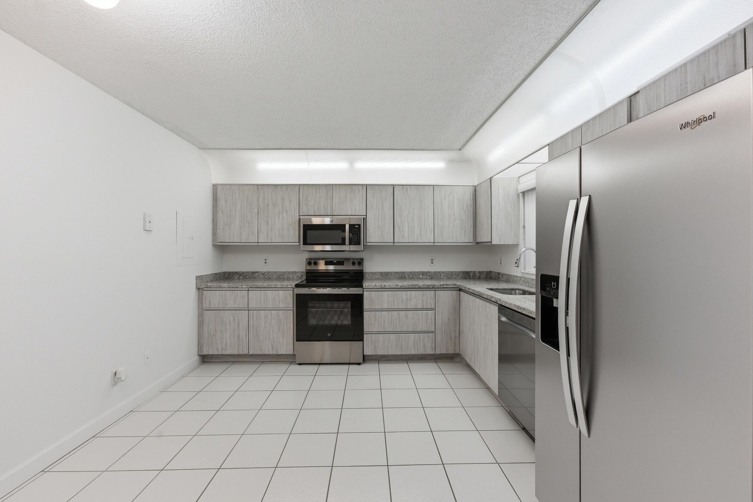 9633 Riverside Drive, Unit E3 Coral Springs, FL 33071 - Photo 8 of 31 a kitchen with stainless steel appliances a refrigerator sink and cabinets
