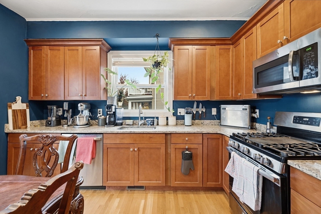 a kitchen with stainless steel appliances granite countertop a stove top oven a sink dishwasher and cabinets with wooden floor