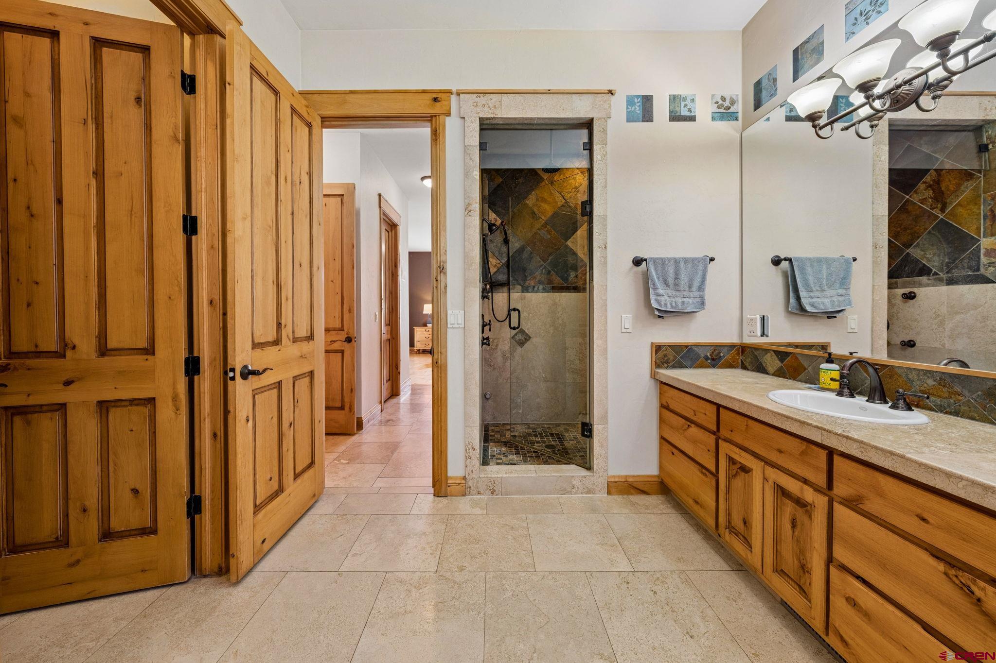 70 Clear Creek Loop Durango, CO 81301 - Photo 17 of 35 a spacious bathroom with a mirror a double vanity sink and glass door
