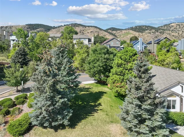 an aerial view of residential houses with outdoor space and trees
