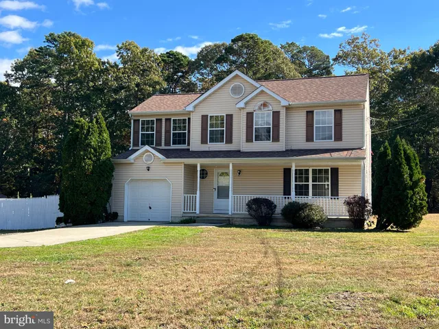 a view of a white house with a large windows and a yard with plants and large trees