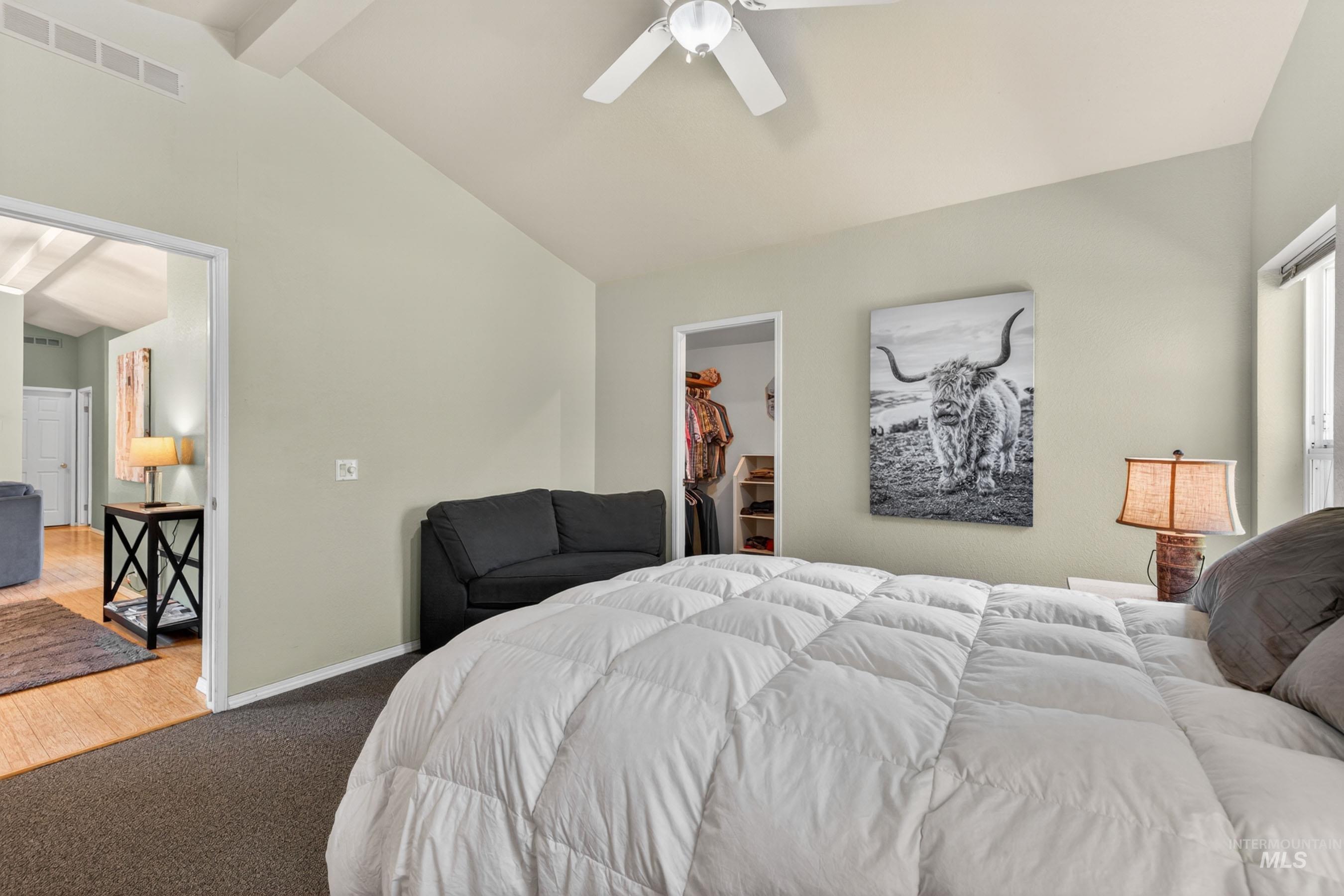 151 Cow Creek Road Lucile, ID 83542 - Photo 21 of 50 Vaulted ceiling with exposed beams and ceiling fan, plush carpet flooring, recessed closet, and an open doorway to an adjoining room with wood-finish flooring