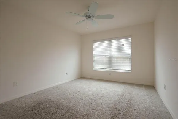 an empty room with a window and a ceiling fan