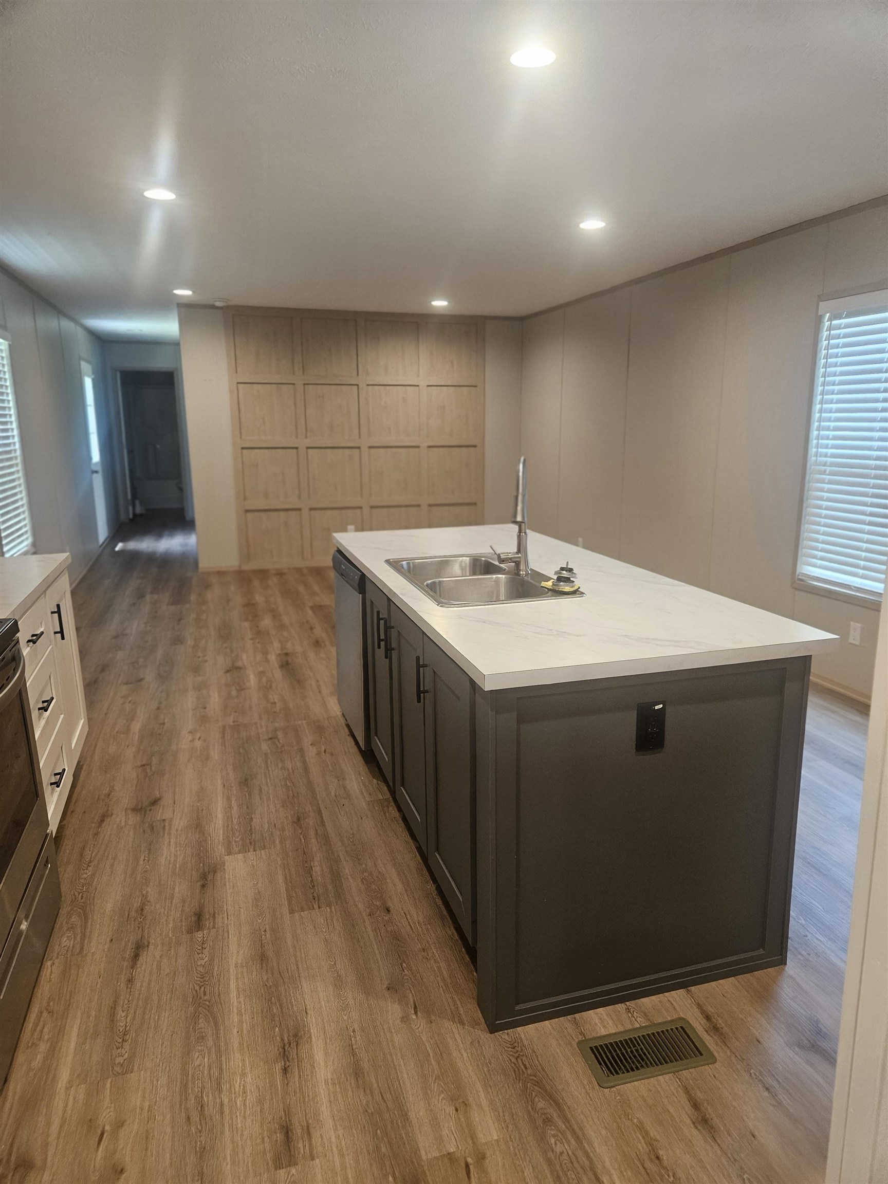 75 Pittman Road, Unit ROAD Somerville, TN 38068 - Photo 4 of 26 Spacious kitchen featuring a large island with a double basin sink, light-toned countertops, dark cabinetry, and wood-finish flooring