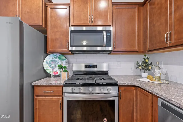 a kitchen with stainless steel appliances granite countertop a refrigerator a sink a stove and a microwave oven with wooden floor