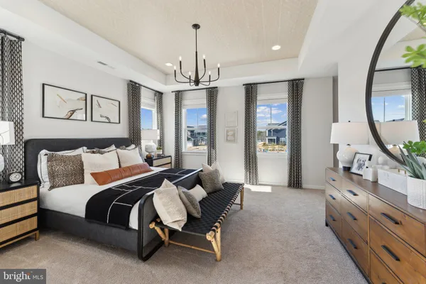 a spacious bedroom with a bed a dresser and potted plant on the dresser