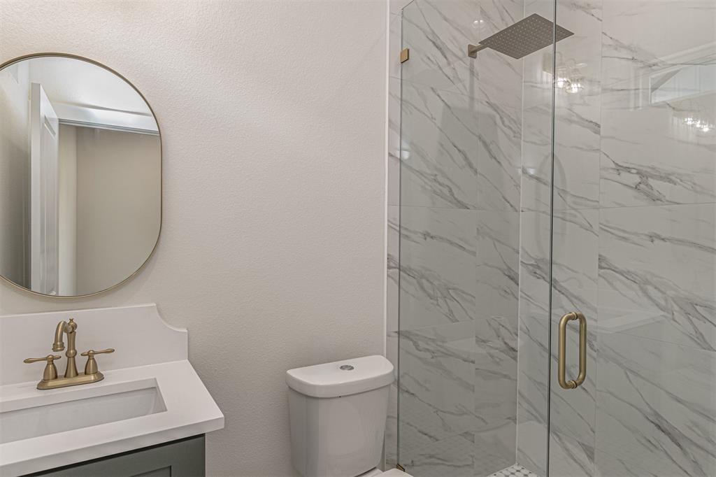 360 Dalton Road Canton, TX 75103 - Photo 22 of 33 Bathroom featuring a walk-in shower with clear glass enclosure and marble-look tile walls, a rain showerhead, a vanity with a white countertop and undermount sink, a bronze-finish faucet, and an oval mirror