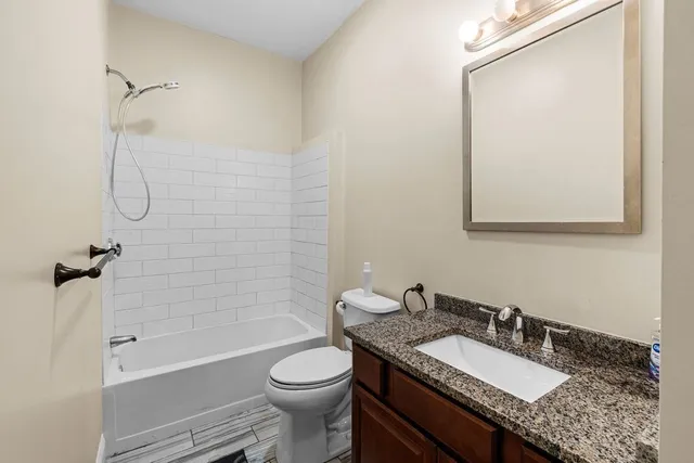 a bathroom with a granite countertop sink toilet a mirror and shower