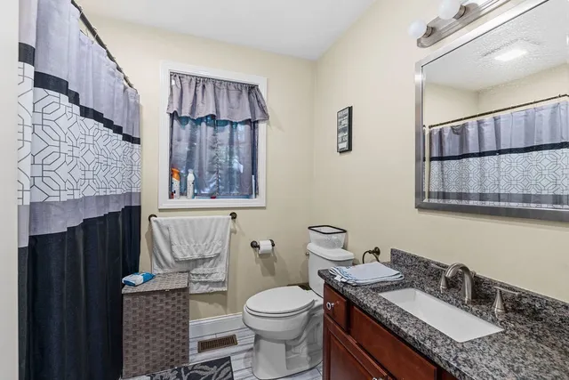 a bathroom with a granite countertop toilet sink and mirror