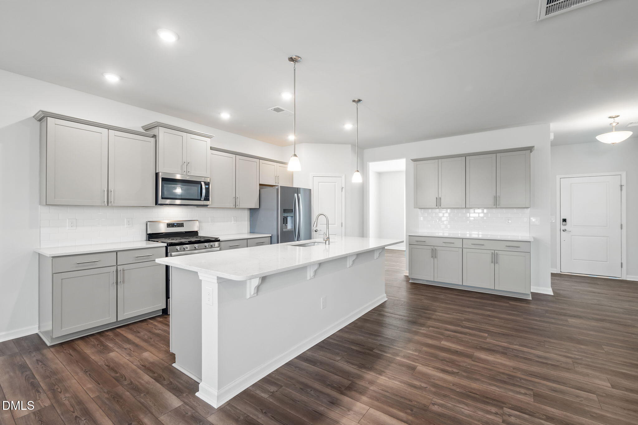 701 Mayfly Way Durham, NC 27703 - Photo 9 of 50 a large white kitchen with kitchen island a sink a stove a refrigerator and white cabinets with wooden floor