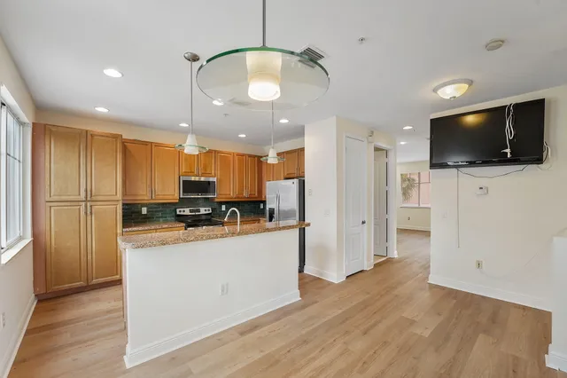 a kitchen with stainless steel appliances granite countertop a refrigerator a sink dishwasher a stove and white countertops with wooden floor