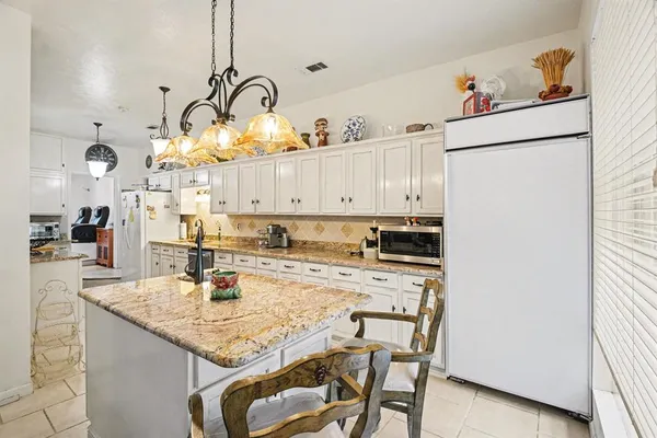 a kitchen with kitchen island granite countertop a stove a sink and white cabinets with wooden floor