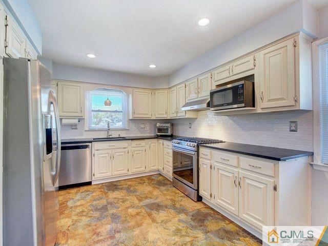 33 Thomas Road East Brunswick, NJ 08816 - Photo 8 of 28 a kitchen with granite countertop a stove top oven microwave and cabinets