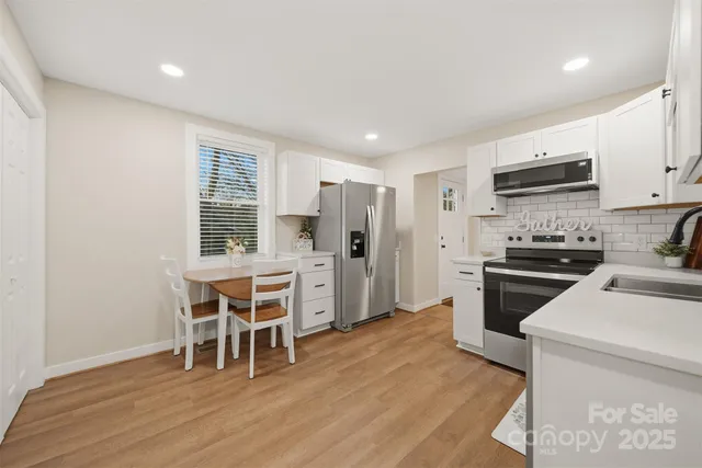 a kitchen with stainless steel appliances kitchen island granite countertop a stove a refrigerator a sink a dining table and chairs with wooden floor