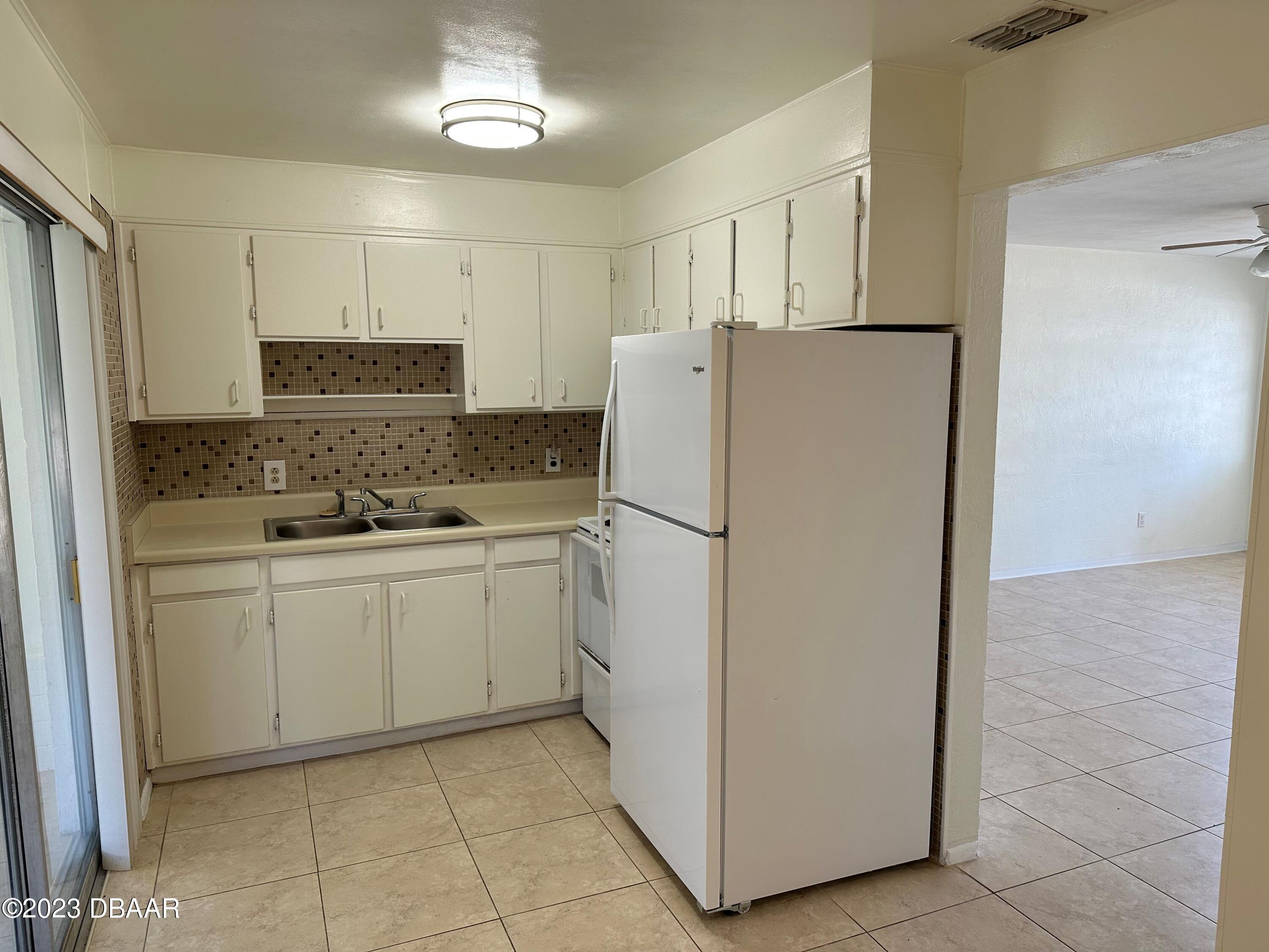 38 Carol Road Ormond Beach, FL 32176 - Photo 4 of 16 a kitchen with a refrigerator a stove top oven and cabinets