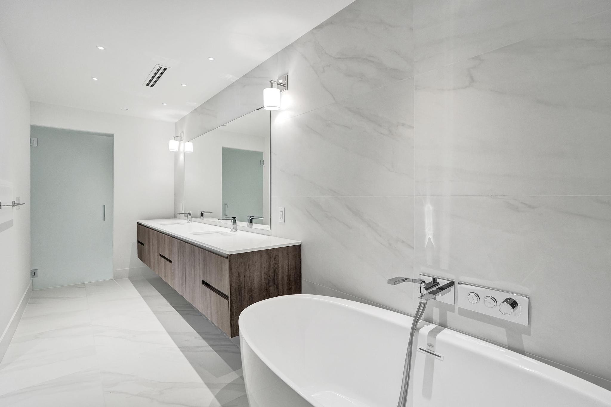 407 North Riverside Drive, Unit 303 Pompano Beach, FL 33062 - Photo 21 of 74 a bathroom with a double vanity sink a mirror and a bathtub