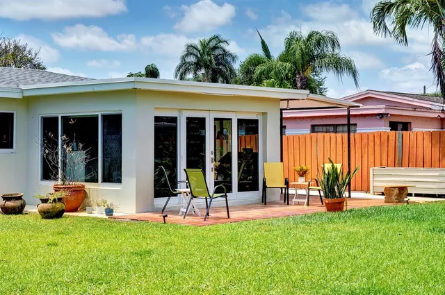 a view of a patio with table and chairs with a yard potted plants and a large tree